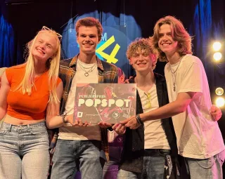 De vier bandleden van KeyKey and the Locks poseren met een cheque van de publieksprijs